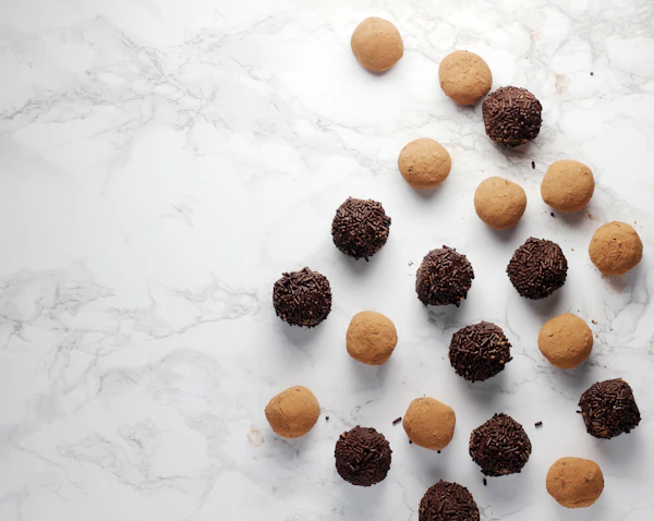 Cocoa and chocolate truffles on a white surface