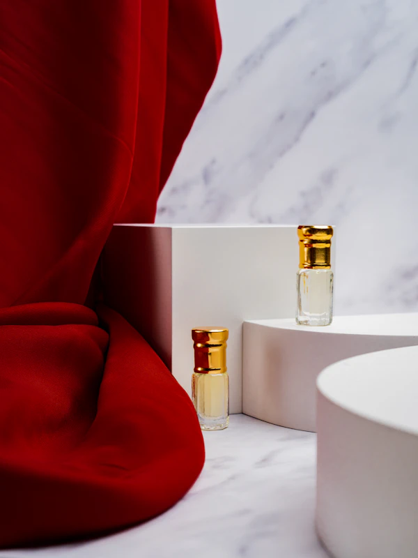 Two golden fragrance bottles on white display stands