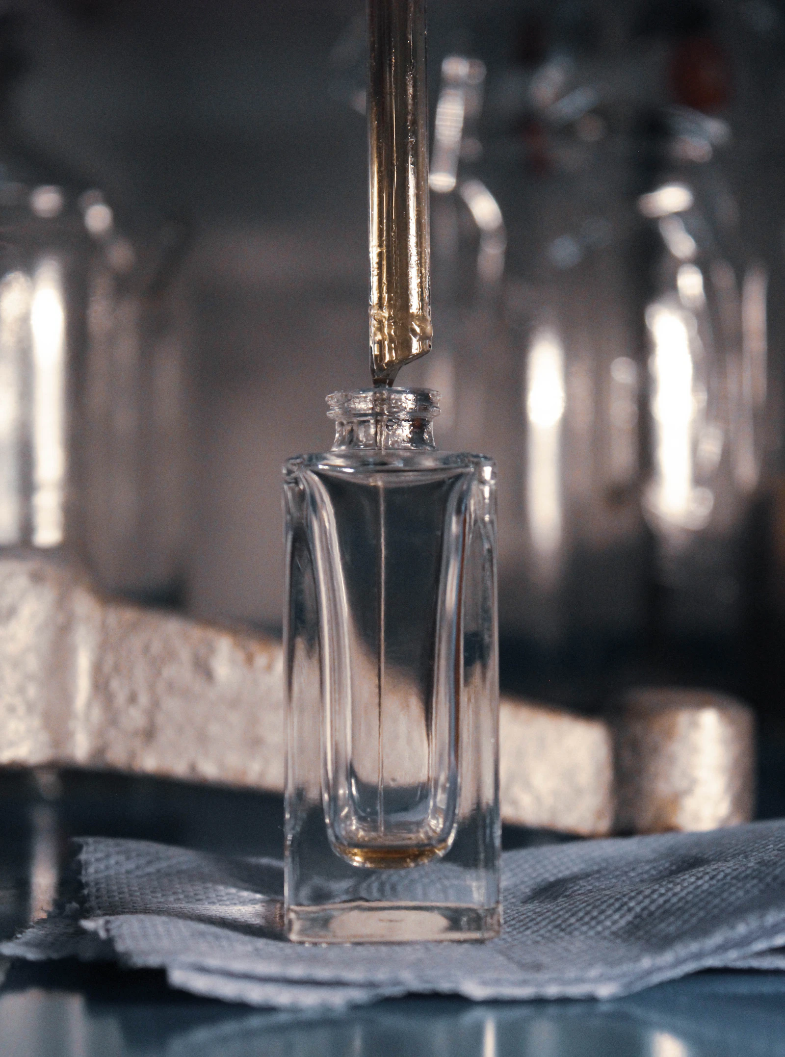 A pipette above a clear perfume bottle